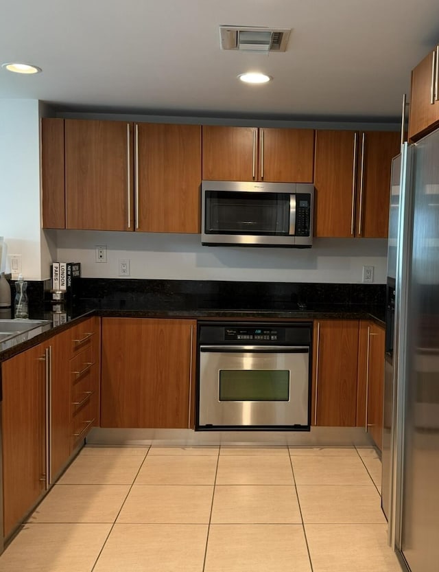 610 Clematis St Unit 336, West Palm Beach, FL 33401 - kitchen with appliances with stainless steel finishes, light tile patterned floors, brown cabinets, dark stone countertops, and recessed lighting