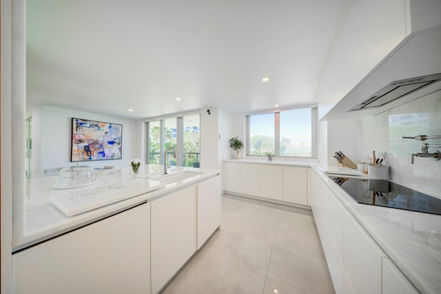 901 E Camino Real Unit 2A, Boca Raton, FL 33432 - kitchen with black electric stovetop, a sink, white cabinets, light tile patterned flooring, and recessed lighting
