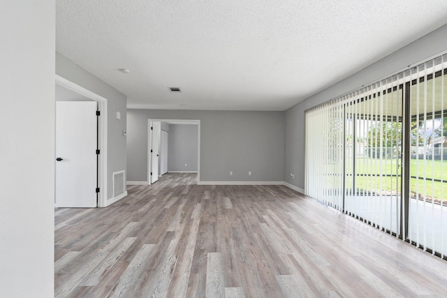2307 SE Seafury Ln SE, Port Saint Lucie, FL 34952 - unfurnished room with light wood finished floors, a textured ceiling, and baseboards