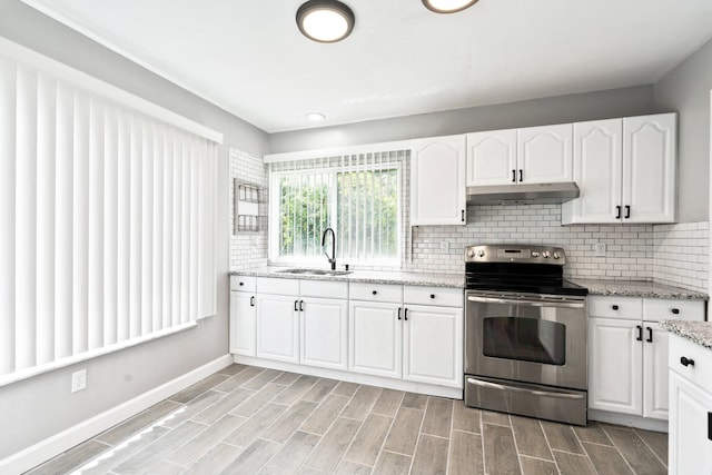 2307 SE Seafury Ln SE, Port Saint Lucie, FL 34952 - kitchen with stainless steel range with electric stovetop, under cabinet range hood, a sink, white cabinetry, and backsplash