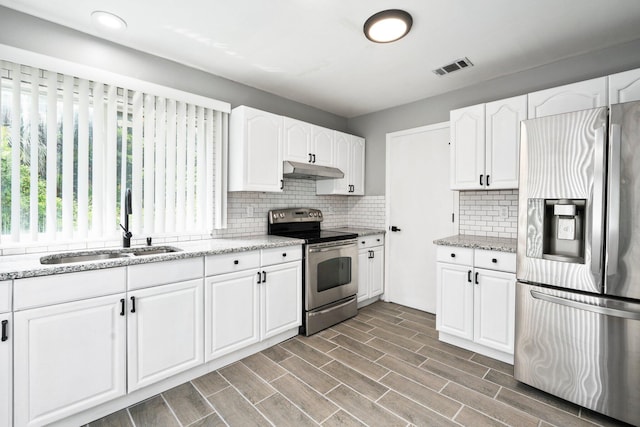 2307 SE Seafury Ln SE, Port Saint Lucie, FL 34952 - kitchen with stainless steel appliances, under cabinet range hood, a sink, tasteful backsplash, and white cabinets