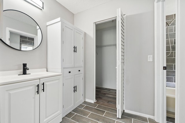 2307 SE Seafury Ln SE, Port Saint Lucie, FL 34952 - full bathroom with vanity, a textured ceiling, wood finished floors, a walk in closet, and baseboards