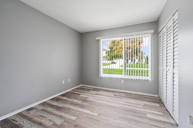 2307 SE Seafury Ln SE, Port Saint Lucie, FL 34952 - unfurnished bedroom featuring wood finished floors, a textured ceiling, baseboards, and a closet