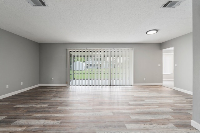 2307 SE Seafury Ln SE, Port Saint Lucie, FL 34952 - spare room with wood finished floors, a textured ceiling, and baseboards
