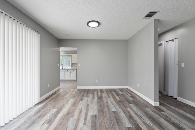 2307 SE Seafury Ln SE, Port Saint Lucie, FL 34952 - unfurnished living room featuring light wood-style floors, baseboards, a sink, and a textured ceiling