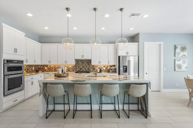 983 Hookline Cir, The Acreage, FL 33470 - kitchen with appliances with stainless steel finishes, a sink, tasteful backsplash, a kitchen breakfast bar, and recessed lighting