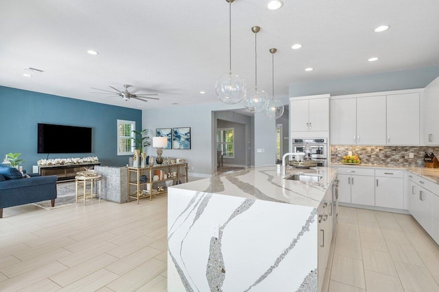 983 Hookline Cir, The Acreage, FL 33470 - kitchen featuring recessed lighting, a ceiling fan, open floor plan, backsplash, and white cabinetry