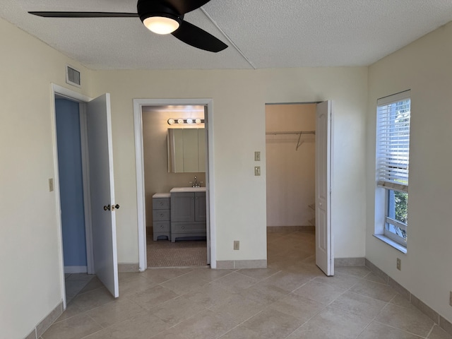 7535 S Orile Blvd Unit 108, Delray Beach, FL 33446 - unfurnished bedroom with a textured ceiling, multiple windows, a walk in closet, ensuite bath, and a closet