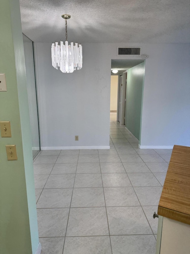 7535 S Orile Blvd Unit 108, Delray Beach, FL 33446 - empty room featuring a textured ceiling, a chandelier, light tile patterned floors, and baseboards