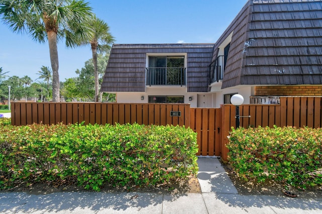 1602 16th Ct Unit 48D, Jupiter, FL 33477 - view of home's exterior with mansard roof, a fenced front yard, and a gate