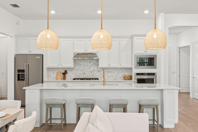 10803 Stellar Cir, Palm Beach Gardens, FL 33412 - kitchen with stainless steel appliances, backsplash, white cabinets, a kitchen bar, and recessed lighting