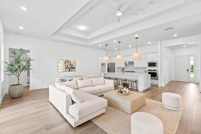 10803 Stellar Cir, Palm Beach Gardens, FL 33412 - living area with light wood-style floors, recessed lighting, ceiling fan, ornamental molding, and a tray ceiling