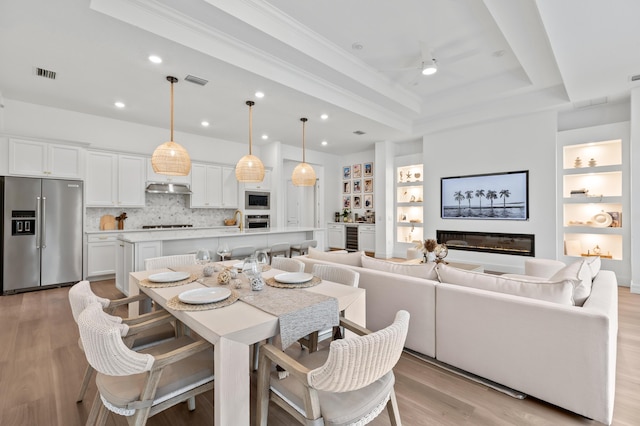 10803 Stellar Cir, Palm Beach Gardens, FL 33412 - dining room with a tray ceiling, light wood-type flooring, built in features, crown molding, and beverage cooler