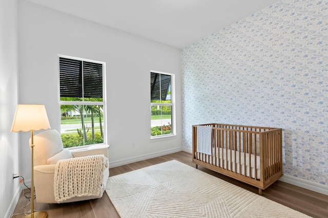 10803 Stellar Cir, Palm Beach Gardens, FL 33412 - bedroom with wood finished floors, wallpapered walls, baseboards, and a nursery area
