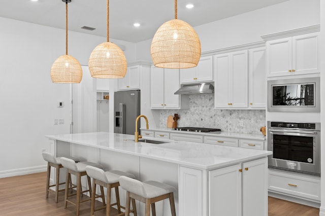 10803 Stellar Cir, Palm Beach Gardens, FL 33412 - kitchen with appliances with stainless steel finishes, a sink, under cabinet range hood, tasteful backsplash, and light wood-type flooring
