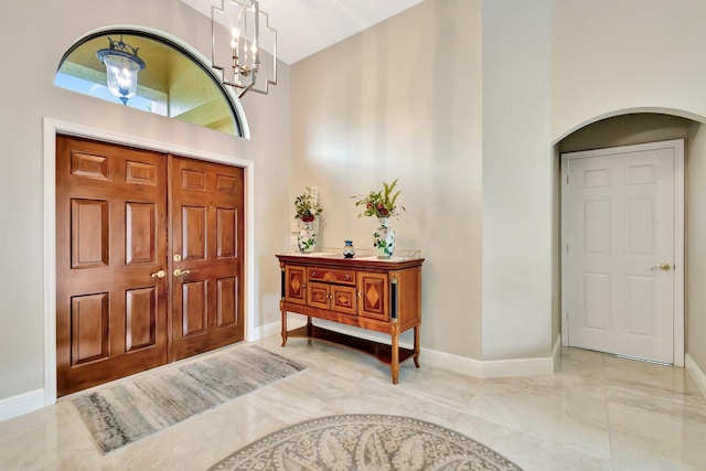 4610 Bucida Rd, Boynton Beach, FL 33436 - foyer featuring arched walkways, a towering ceiling, baseboards, marble finish floors, and a chandelier