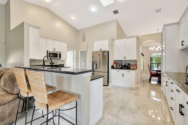 4610 Bucida Rd, Boynton Beach, FL 33436 - kitchen featuring stainless steel appliances, arched walkways, a peninsula, high vaulted ceiling, and tasteful backsplash