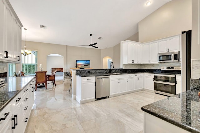 4610 Bucida Rd, Boynton Beach, FL 33436 - kitchen featuring appliances with stainless steel finishes, arched walkways, a peninsula, a sink, and backsplash