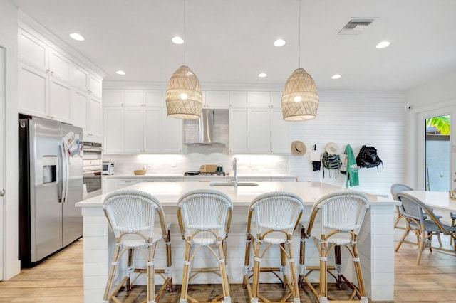 13291 Machiavelli Way, Palm Beach Gardens, FL 33418 - kitchen featuring stainless steel appliances, wall chimney exhaust hood, a sink, light countertops, and light wood finished floors
