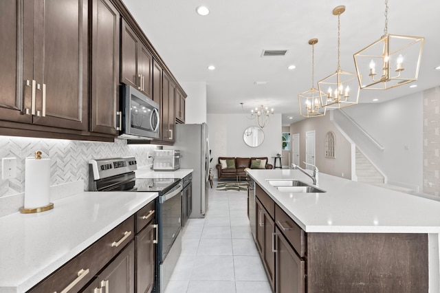 587 Sanderling Cir, Deerfield Beach, FL 33442 - kitchen featuring stainless steel appliances, a sink, dark brown cabinets, a chandelier, and a center island with sink