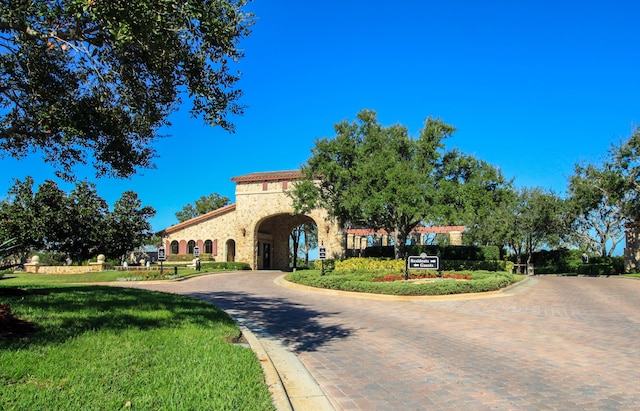 24038 SW Firenze Way, Port Saint Lucie, FL 34986 - mediterranean / spanish-style house with stone siding, curved driveway, and a front yard