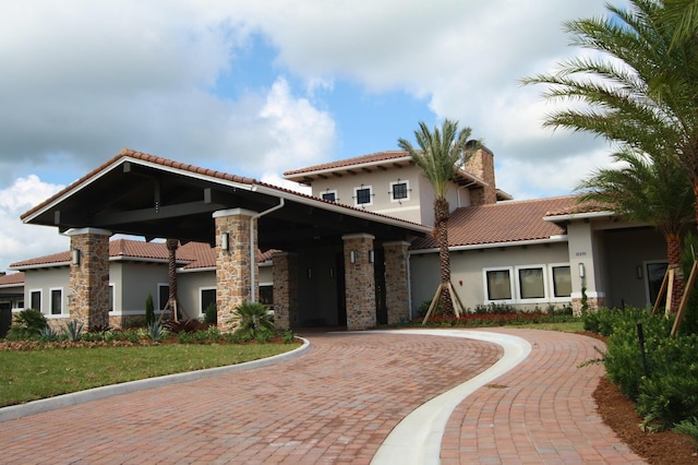 24038 SW Firenze Way, Port Saint Lucie, FL 34986 - mediterranean / spanish house featuring curved driveway, stucco siding, stone siding, and a tile roof