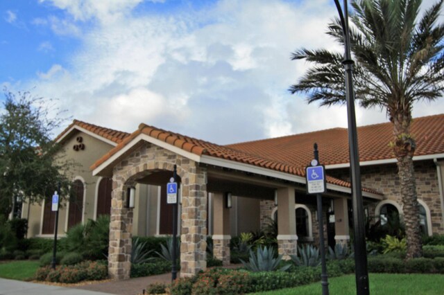 24038 SW Firenze Way, Port Saint Lucie, FL 34986 - view of front facade featuring a tiled roof, stone siding, and stucco siding