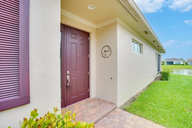 24038 SW Firenze Way, Port Saint Lucie, FL 34986 - doorway to property featuring stucco siding, a water view, and a lawn