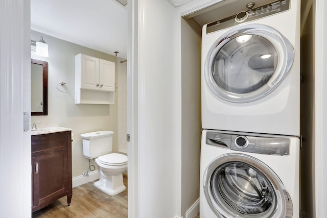 2430 Deer Creek Country Club Blvd Unit 205-2, Deerfield Beach, FL 33442 - washroom with stacked washing machine and dryer and light wood-style floors