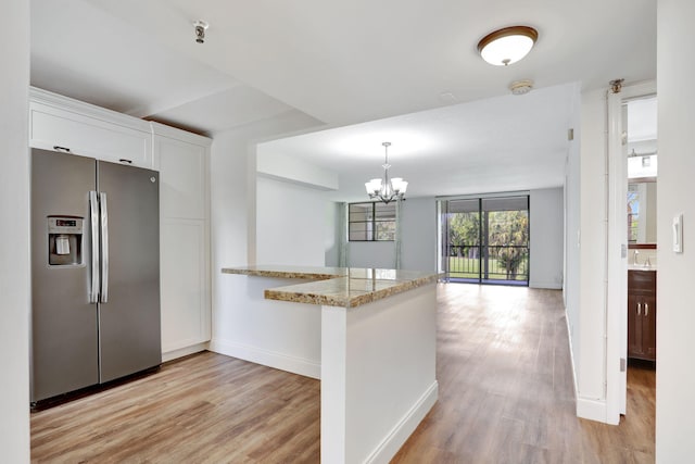 2430 Deer Creek Country Club Blvd Unit 205-2, Deerfield Beach, FL 33442 - kitchen featuring stainless steel fridge, a chandelier, light wood-style flooring, white cabinetry, and a peninsula