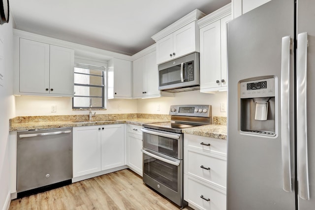 2430 Deer Creek Country Club Blvd Unit 205-2, Deerfield Beach, FL 33442 - kitchen with appliances with stainless steel finishes, light wood-type flooring, white cabinets, and light stone counters