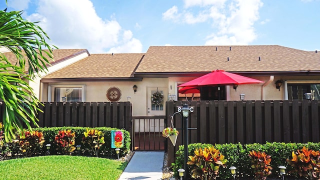804 Sky Pine Way Unit C, Greenacres, FL 33415 - view of front of property with a shingled roof, a fenced front yard, a gate, and stucco siding