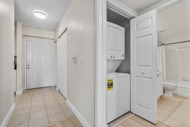 651 Okeechobee Blvd Unit 408, West Palm Beach, FL 33401 - laundry area featuring stacked washer / dryer, light tile patterned floors, a textured ceiling, and baseboards