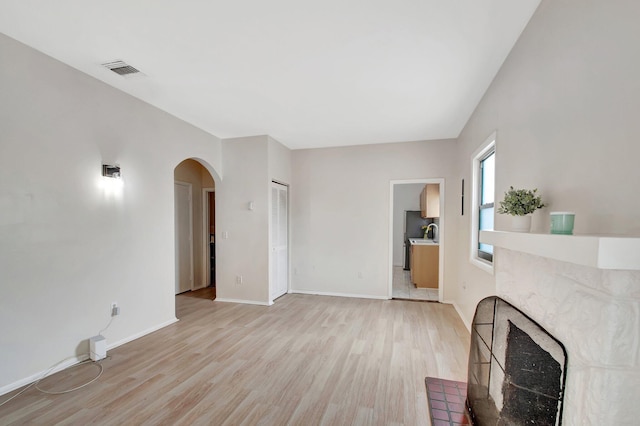 701 S J St, Lake Worth Beach, FL 33460 - living area featuring arched walkways, light wood-style floors, baseboards, and a high end fireplace