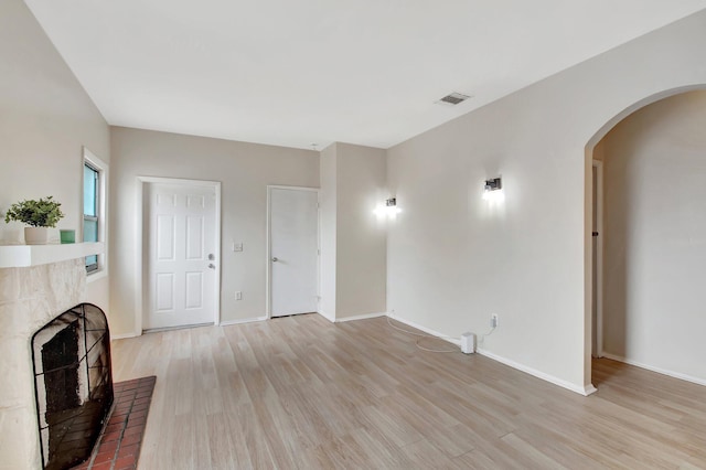 701 S J St, Lake Worth Beach, FL 33460 - unfurnished living room featuring light wood finished floors, a brick fireplace, arched walkways, and baseboards