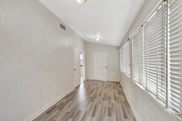701 S J St, Lake Worth Beach, FL 33460 - hallway with light wood-style flooring, plenty of natural light, vaulted ceiling, baseboards, and a textured wall