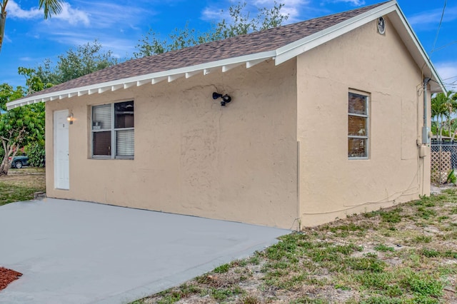 701 S J St, Lake Worth Beach, FL 33460 - view of side of property featuring roof with shingles, a patio, and stucco siding