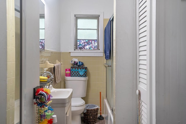 713 10th Ave N, Lake Worth Beach, FL 33460 - full bath featuring toilet, tile walls, vanity, a wainscoted wall, and enclosed tub / shower combo