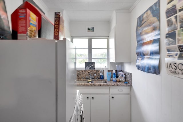 713 10th Ave N, Lake Worth Beach, FL 33460 - kitchen with freestanding refrigerator, ornamental molding, a sink, white cabinetry, and stone counters