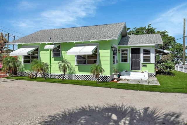 713 10th Ave N, Lake Worth Beach, FL 33460 - view of front of house with roof with shingles, entry steps, and a front lawn