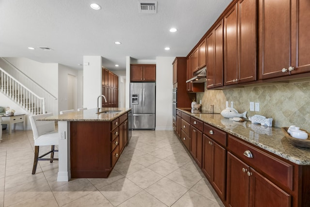 2757 Wymberly Dr, Jupiter, FL 33458 - kitchen featuring appliances with stainless steel finishes, a sink, light tile patterned floors, a kitchen breakfast bar, and decorative backsplash
