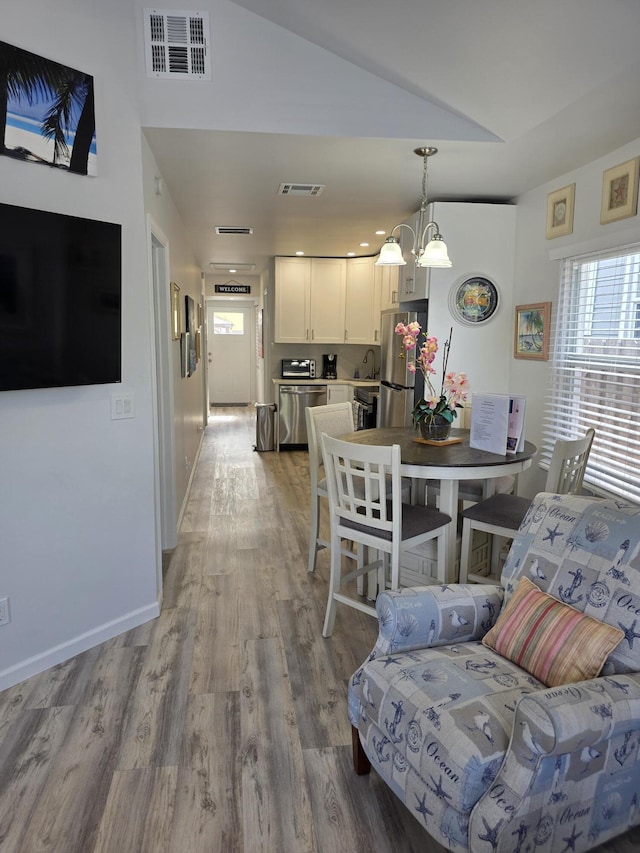 319 N J St, Lake Worth Beach, FL 33460 - living area featuring healthy amount of natural light, light wood finished floors, a chandelier, lofted ceiling, and baseboards