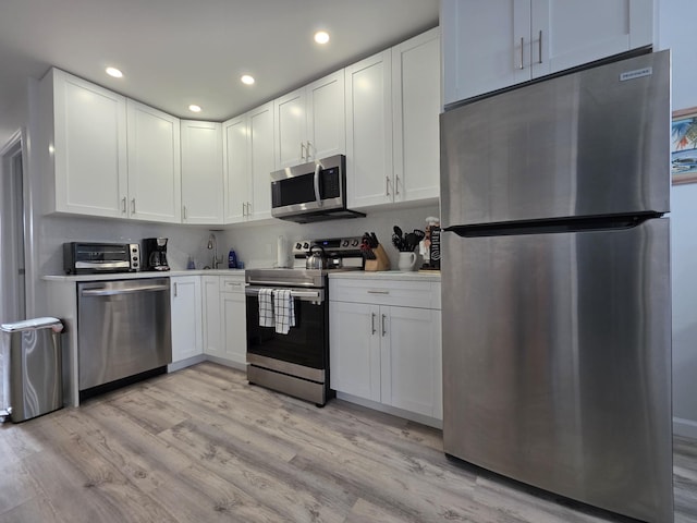 319 N J St, Lake Worth Beach, FL 33460 - kitchen with stainless steel appliances, light wood-style floors, white cabinetry, and recessed lighting