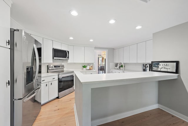 1124 Marine Way W D2R + Boat Slip 19, North Palm Beach, FL 33408 - kitchen featuring stainless steel appliances, a peninsula, light countertops, white cabinets, and light wood-type flooring