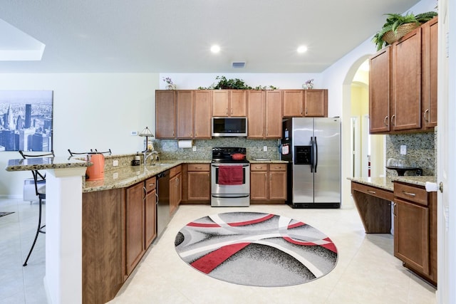 17560 72nd Rd N, The Acreage, FL 33470 - kitchen featuring appliances with stainless steel finishes, a peninsula, decorative backsplash, a breakfast bar, and arched walkways