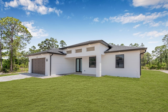 620 Raintree St E, Lehigh Acres, FL 33974 - prairie-style home with a garage, stucco siding, concrete driveway, roof with shingles, and a front lawn
