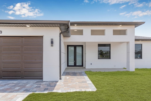620 Raintree St E, Lehigh Acres, FL 33974 - view of front of property with french doors, stucco siding, a front lawn, and a garage
