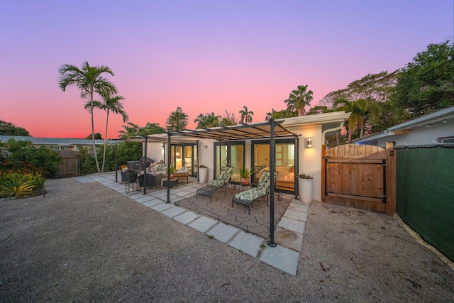 1501 S Palmway, Lake Worth, FL 33460 - back of property at dusk featuring outdoor lounge area, a gate, a patio area, a fenced backyard, and stucco siding