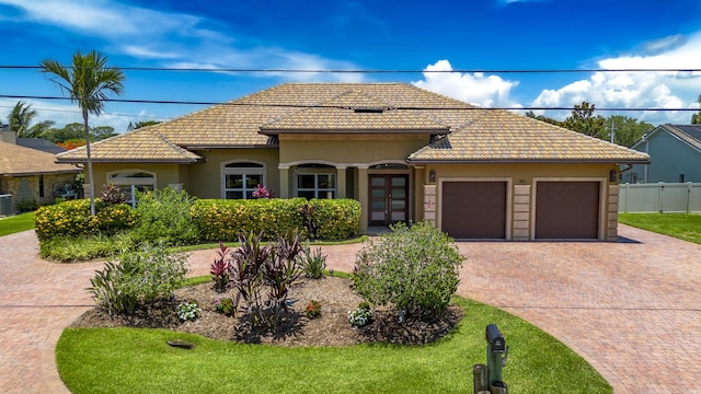 401 SE Verada Ave, Port Saint Lucie, FL 34983 - mediterranean / spanish house with french doors, a garage, decorative driveway, stucco siding, and a tile roof