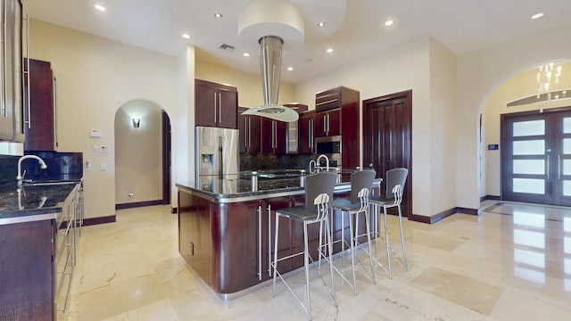 401 SE Verada Ave, Port Saint Lucie, FL 34983 - kitchen with reddish brown cabinets, arched walkways, stainless steel appliances, backsplash, and baseboards